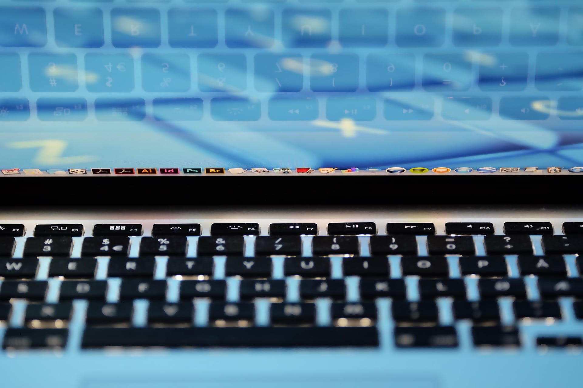 A close-up, shallow-depth-of-field shot of a laptop keyboard and screen, reflecting a **saas startu**p environment with various design and productivity applications visible in the taskbar.